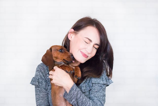 Smiling woman with dark hair holding a dachsund